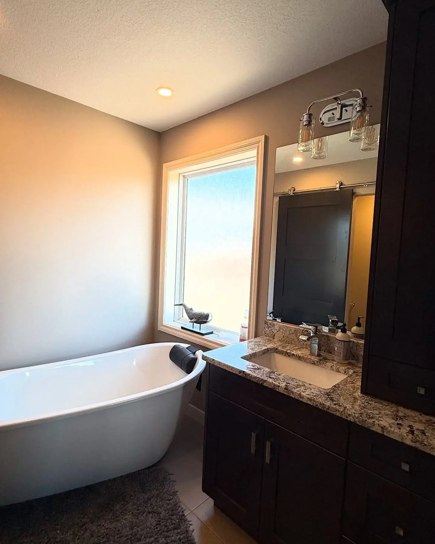 Spa-Style Ensuite with Soaker Tub — Warm walls and crisp trim framing a freestanding tub and dark vanity
