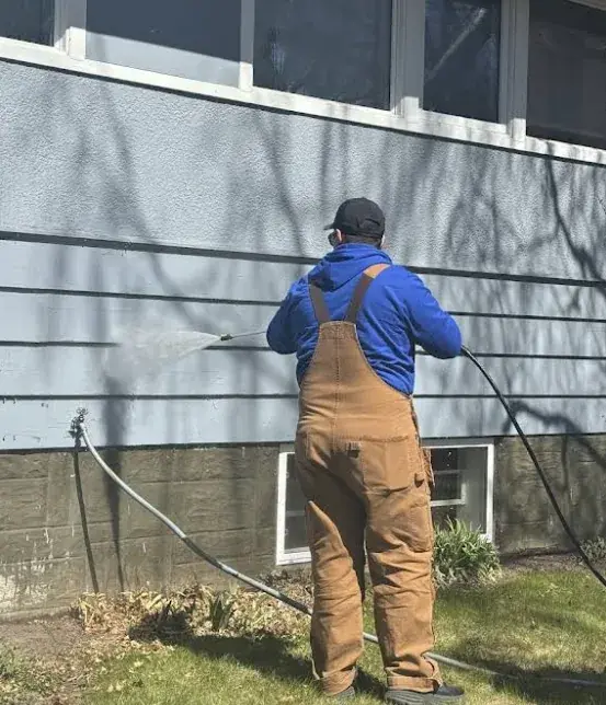 A Chamos Painting crew member pressure-washing a Calgary home to prep the exterior for a durable repaint