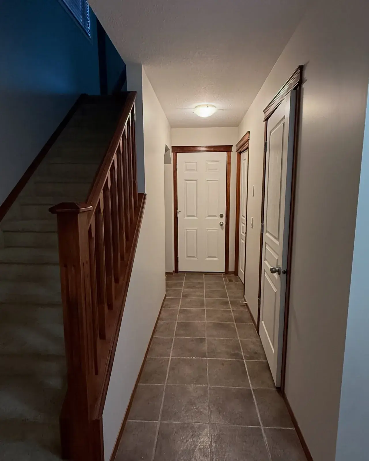 Hallway & Stairwell Repaint — A bright hallway with a bold blue accent at the landing
