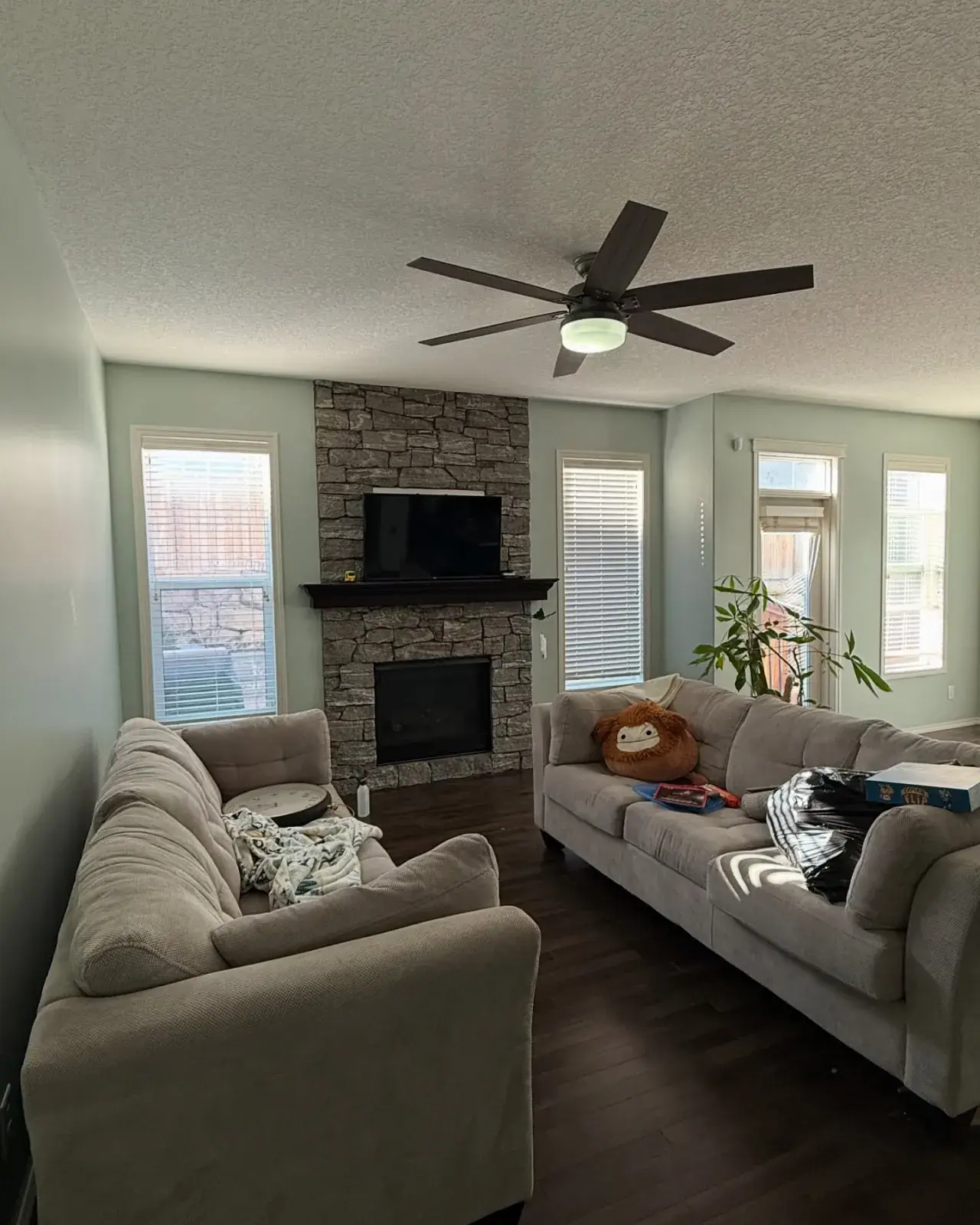 Sage-Toned Living Room Refresh — Soft sage walls, crisp ceiling, and trim around a stone fireplace