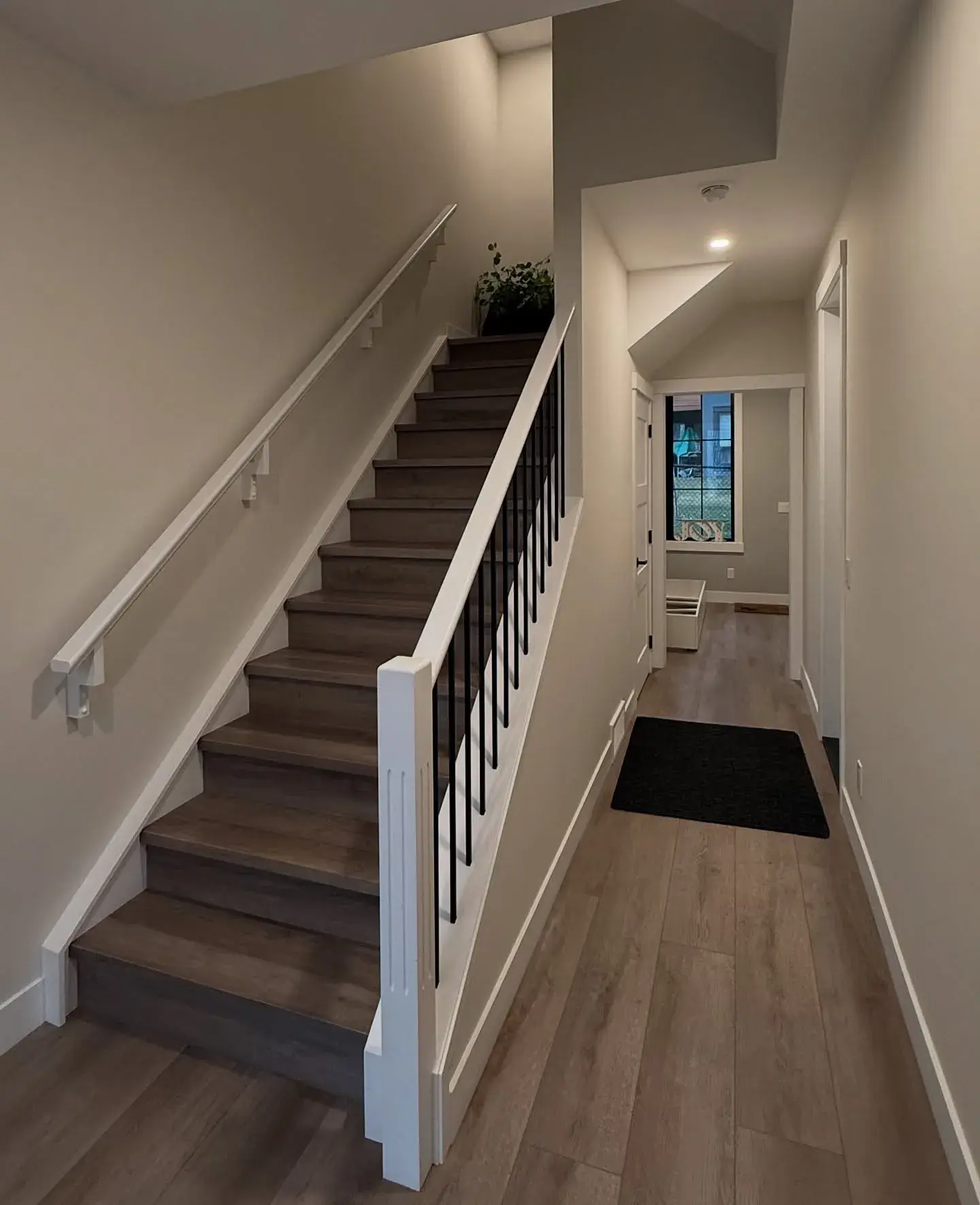 Bright Staircase & Hallway — Soft greige walls and crisp white railings down a stairwell and hall