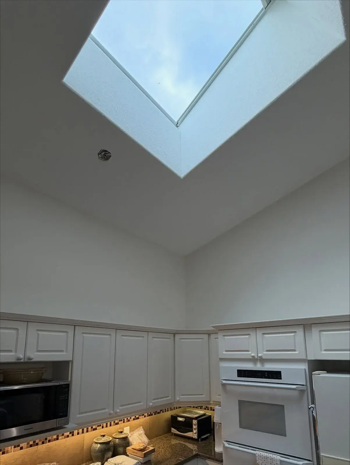 Vaulted Kitchen with Skylight — A bright white kitchen and soaring ceiling finished around a skylight