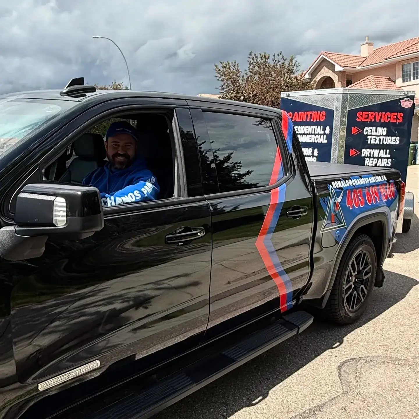 Ronald, owner of Chamos Painting, smiling from the cab of the branded company truck in Calgary