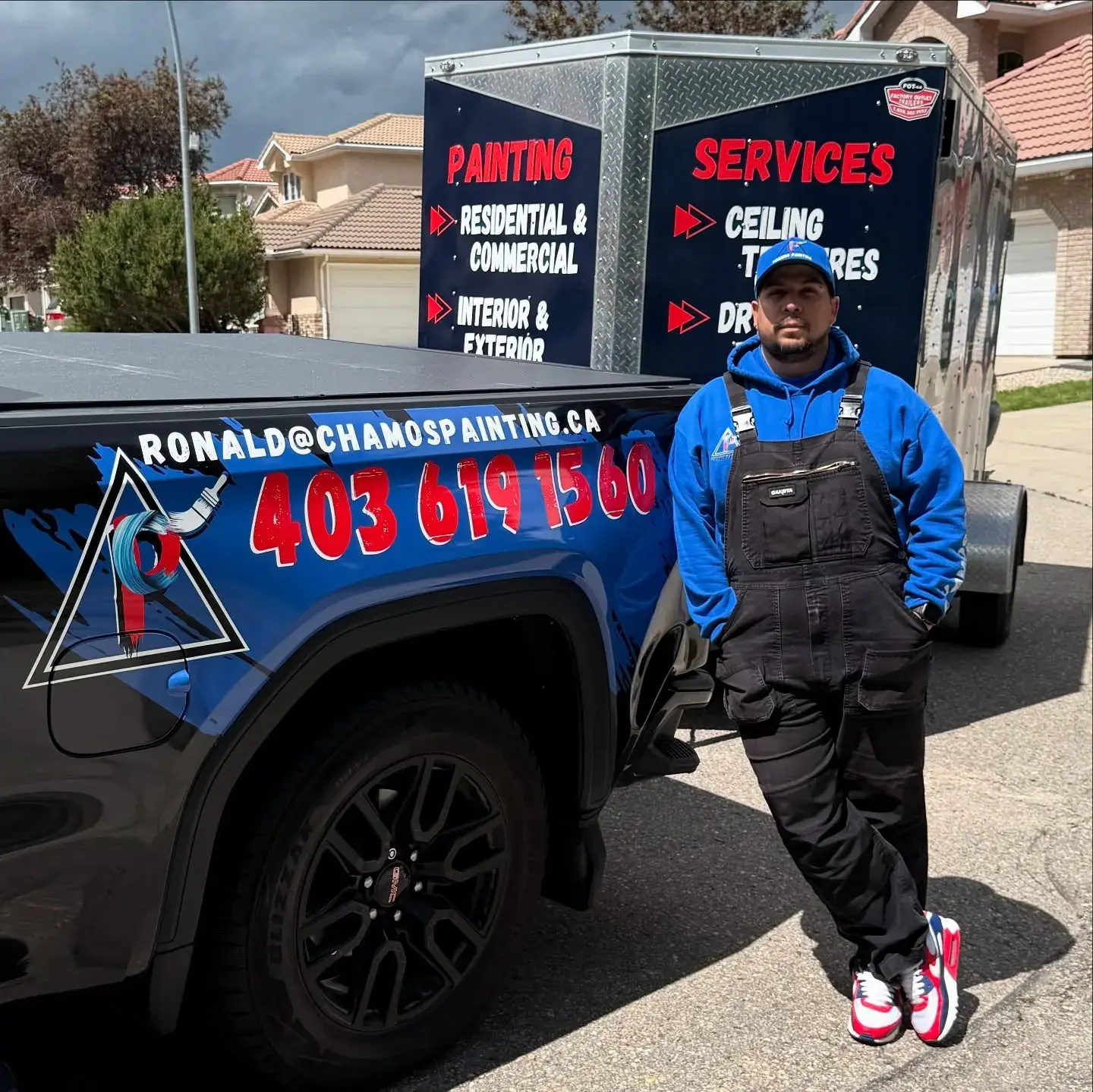 A Chamos Painting team member beside the branded truck and services trailer on a Calgary painting project